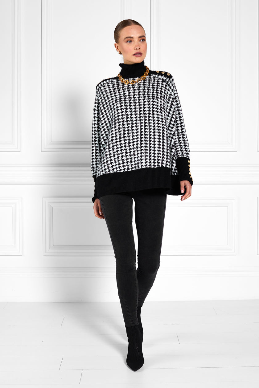 womens funnel neck batwing shaped cape in a white and black houndstooth knit with split side detail and contrast black neckline cuffs and hem