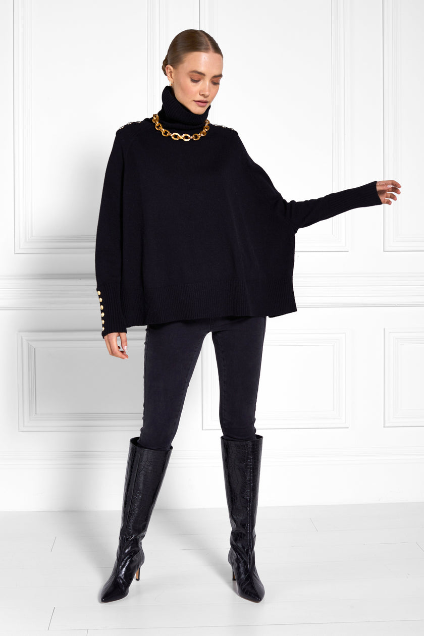 womens funnel neck batwing shaped cape in black knit with split side detail and ribbed neckline cuffs and hem