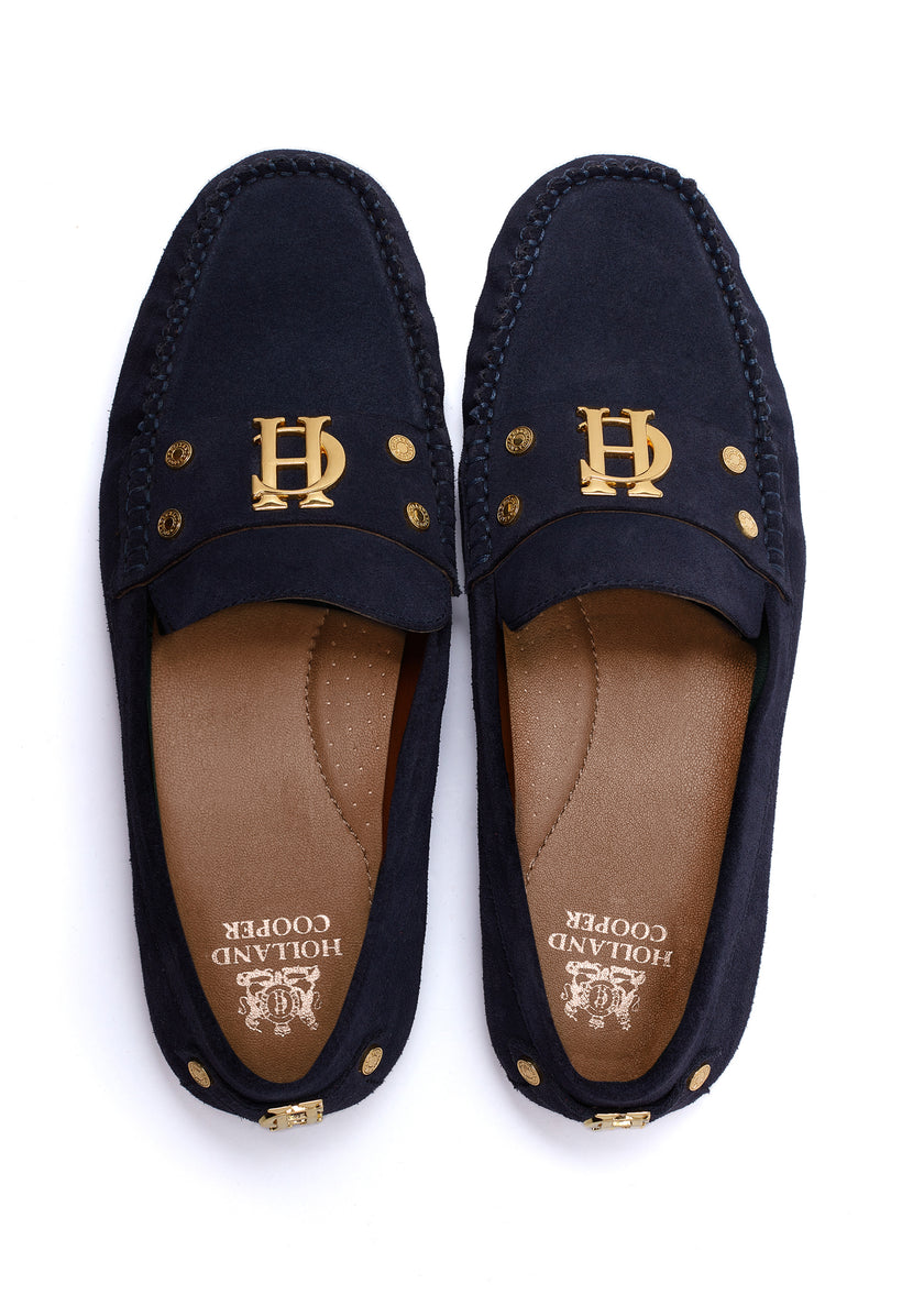 navy suede loafers with a leather sole and top stitching details and gold hardware with gold foil branding on the inner sole