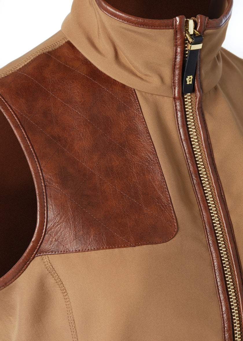 detail shot of the gun patch on the womens light brown gilet with dark brown leather seams along the arm holes pockets and down the zip