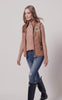 womens light brown gilet with dark brown leather seams along the arm holes pockets and down the zip with a gun patch on the shoulder and an embroidered logo worn with a beige knitted jumper and denim ripped skinny jeans and navy wellington boots